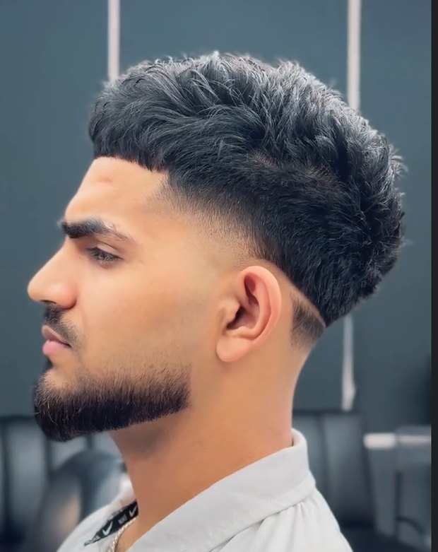 Curly top with a mid fade and beard line-up