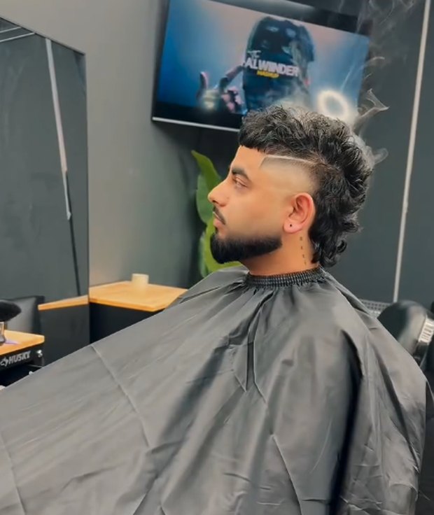 Curly mullet with a hard part and mid fade